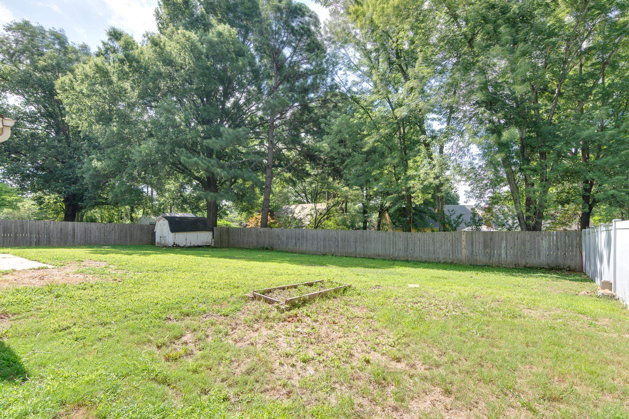 8083 Cinders Road Bartlett, TN 38133 - Photo 30 of 31 Spacious backyard featuring a full perimeter fence, mature trees, an outbuilding, and a raised garden bed