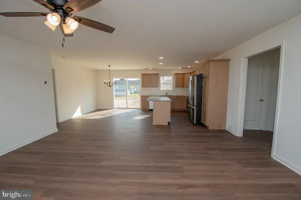 a view of a kitchen with a refrigerator a ceiling fan and wooden floor