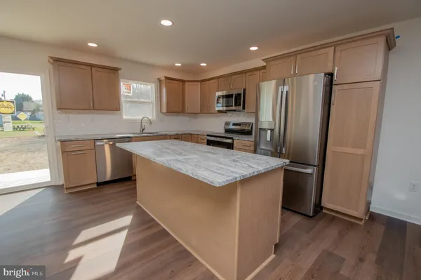 a kitchen with stainless steel appliances granite countertop a refrigerator a sink a stove a microwave and island