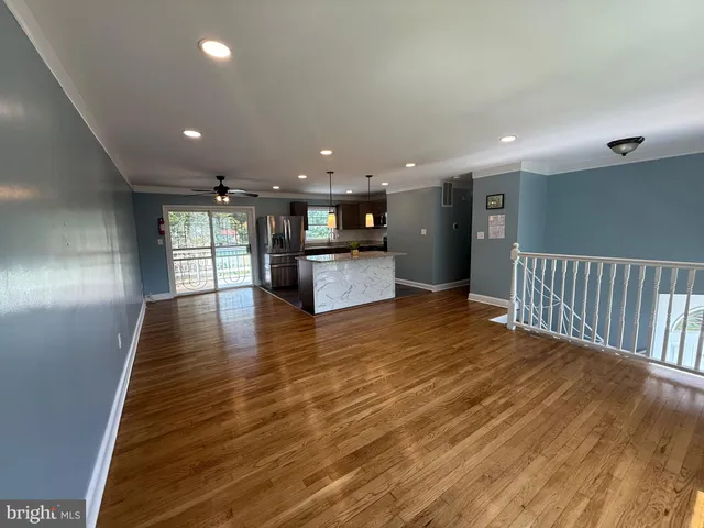 a view of a kitchen with kitchen island wooden floor center island and stainless steel appliances