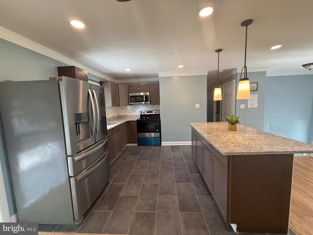 a kitchen with stainless steel appliances granite countertop a refrigerator a sink a stove and oven