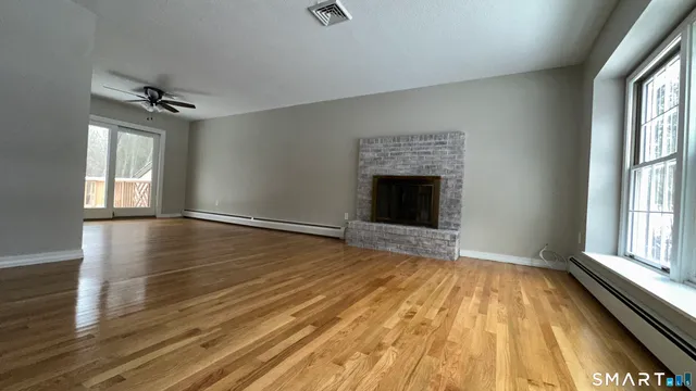 wooden floor fireplace and windows in an empty room