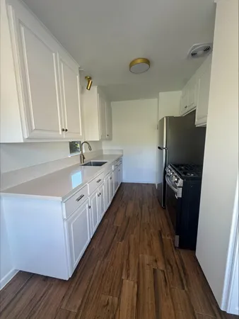 a kitchen with a sink and wooden floor