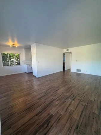 a view of empty room with wooden floor and fan
