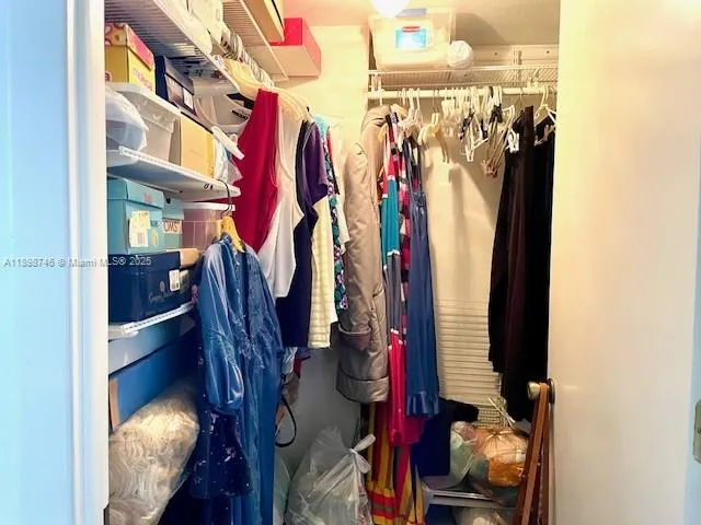 a view of walk in closet with clothes and shoes