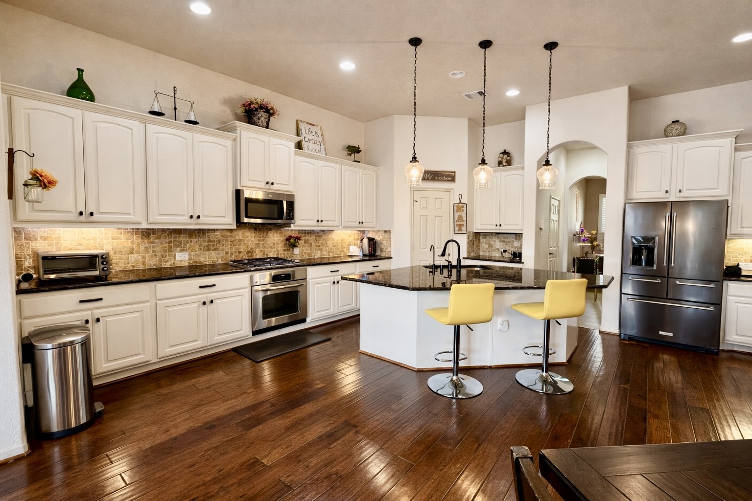 29011 Powder Ridge Drive Katy, TX 77494 - Photo 7 of 25 a kitchen with stainless steel appliances kitchen island granite countertop a stove a sink a refrigerator and white cabinets with wooden floor