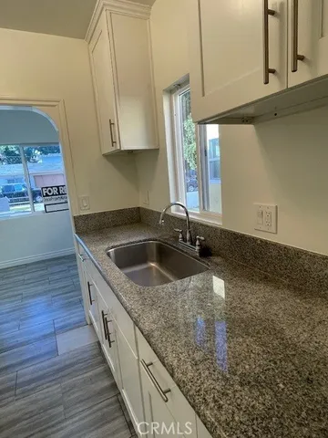 a kitchen with stainless steel appliances granite countertop a sink a stove and a wooden floors