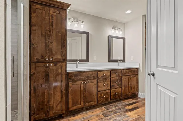 a bathroom with a mirror a double vanity sink and glass door