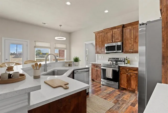 a open kitchen with stainless steel appliances granite countertop a sink dishwasher stove refrigerator and microwave