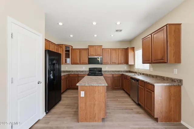 a large kitchen with stainless steel appliances granite countertop a stove top oven a refrigerator and a center island