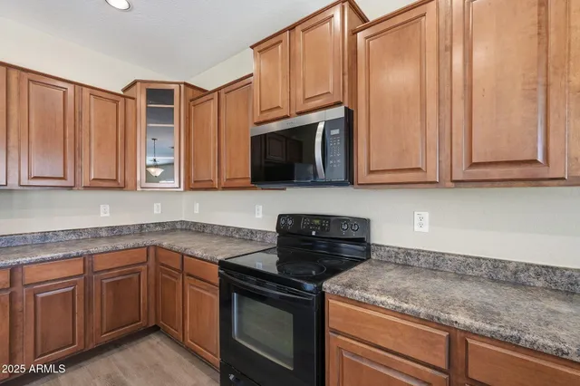 a kitchen with kitchen island granite countertop stainless steel appliances and wooden cabinets