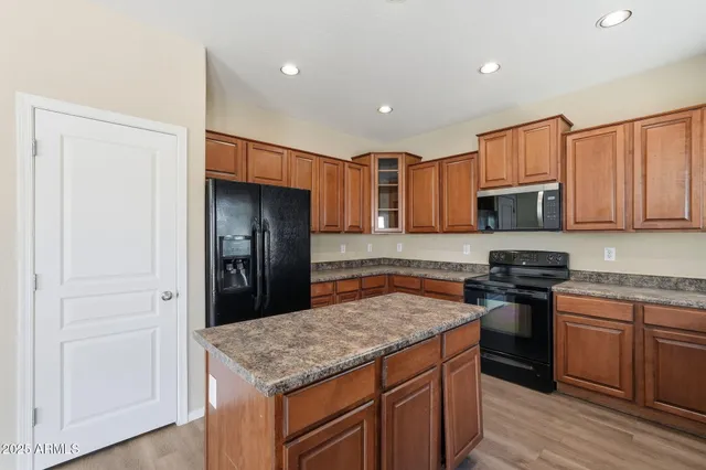 a kitchen with stainless steel appliances kitchen island granite countertop a stove a sink and a refrigerator