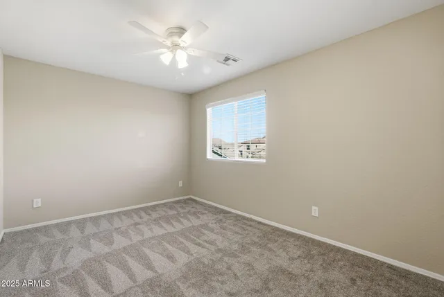 an empty room with a chandelier fan and closet area