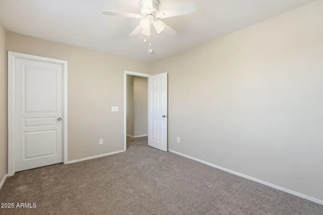 an empty room with closet and a chandelier fan
