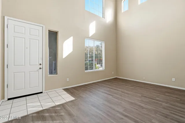 a view of an empty room with window and wooden floor