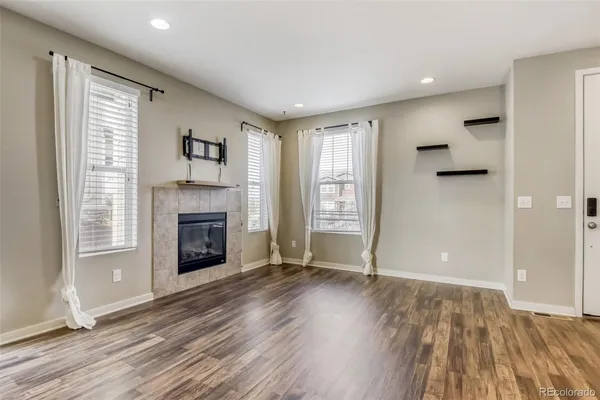 an empty room with wooden floor fireplace and windows