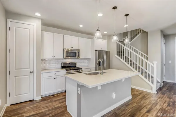 a kitchen with stainless steel appliances kitchen island a refrigerator a stove a sink and a wooden floor