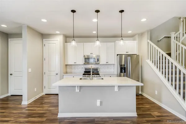 a large kitchen with kitchen island a large counter top stainless steel appliances and a chandelier