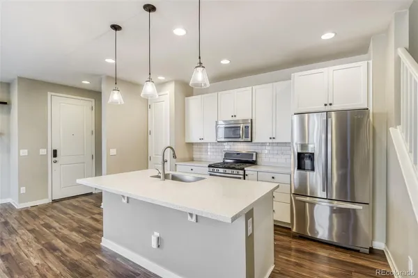 a kitchen with stainless steel appliances granite countertop a sink a refrigerator and a stove