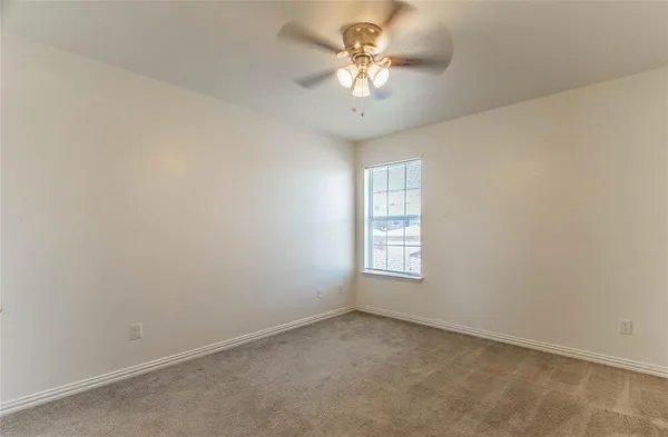 an empty room with a chandelier fan and windows