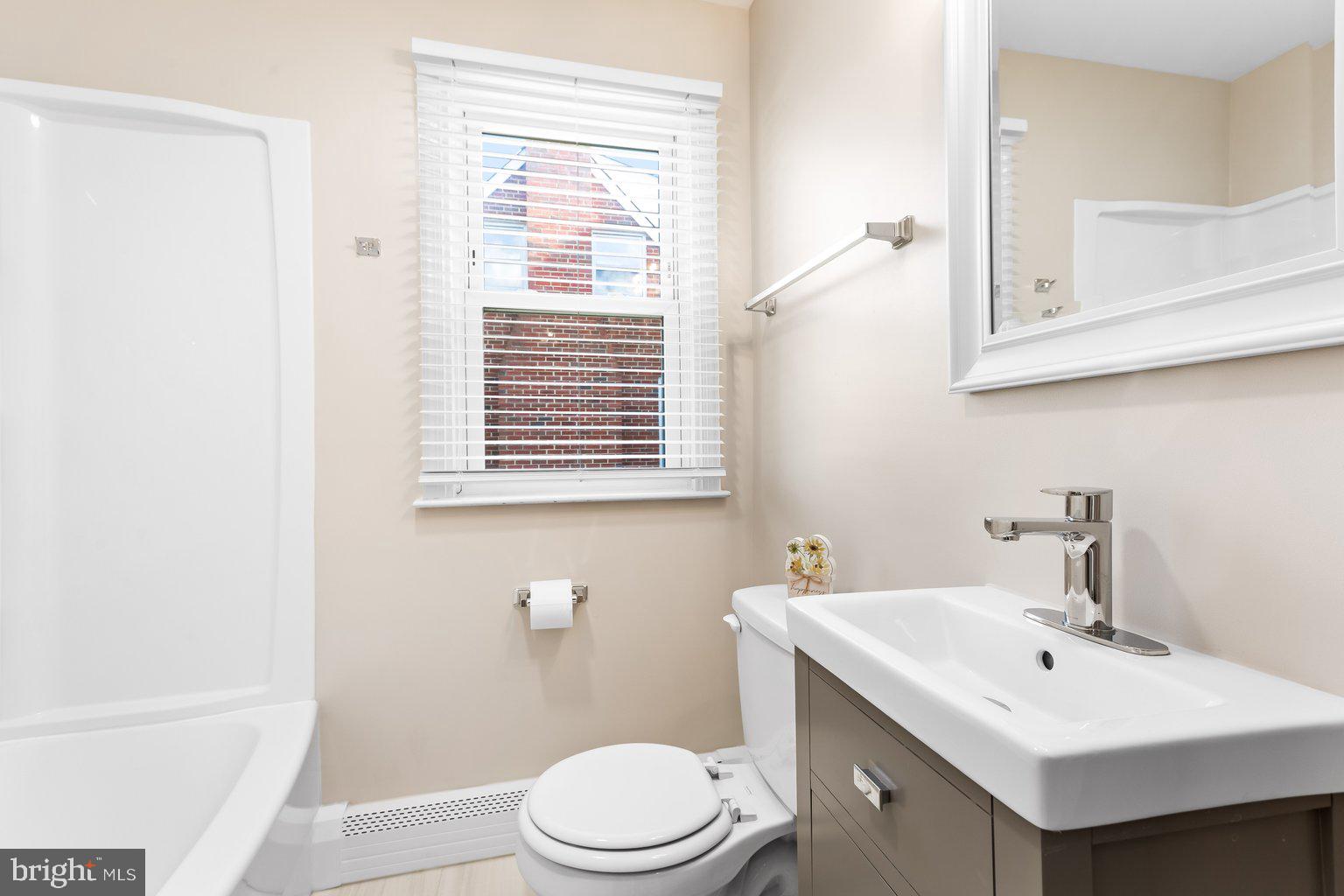 8335 Liberty Road Windsor Mill, MD 21244 - Photo 29 of 57 a bathroom with a toilet a sink a mirror and a window