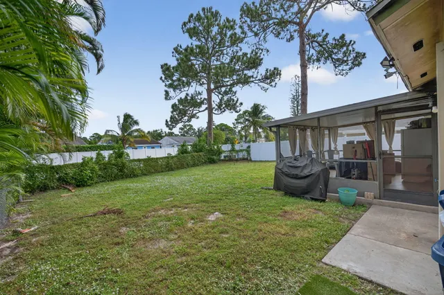 a view of a backyard with table and chairs potted plants and large tree
