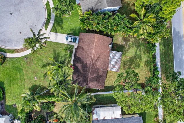an aerial view of a house with a yard lake and trees all around
