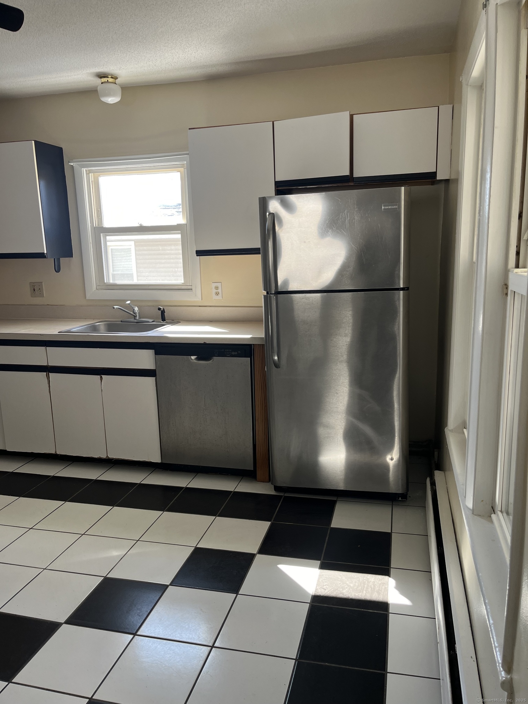 61 School Street Naugatuck, CT 06770 - Photo 2 of 6 a kitchen with a black white checkered floor and a refrigerator