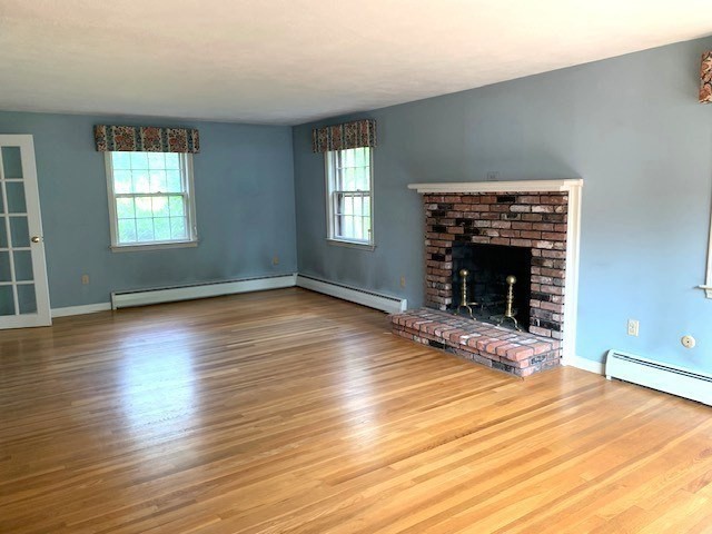 72 Bailey Lane Georgetown, MA 01833 - Photo 4 of 29 an empty room with wooden floor fireplace and windows