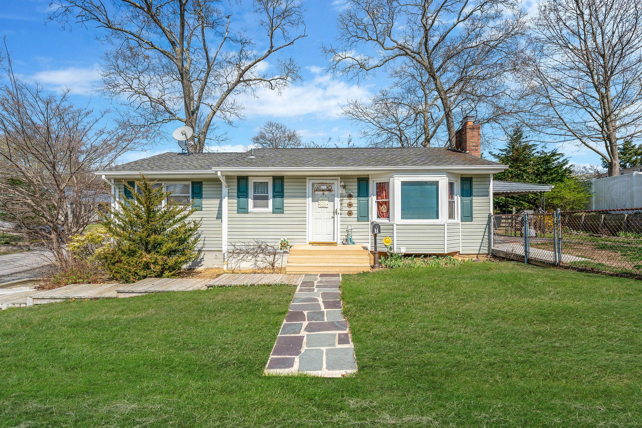 View of front facade with a chimney, a front lawn, a carport, a shingled roof, and fence
