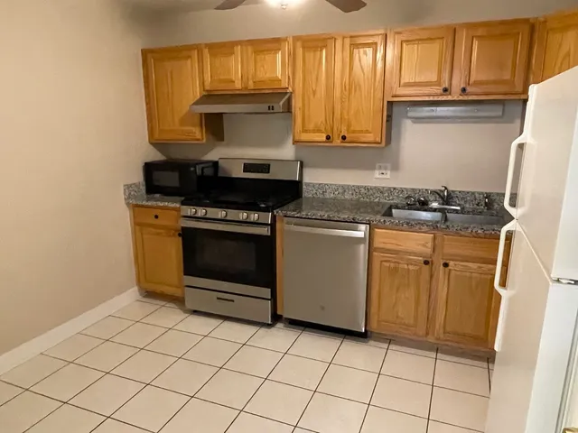 a kitchen with granite countertop a stove top oven microwave and cabinets