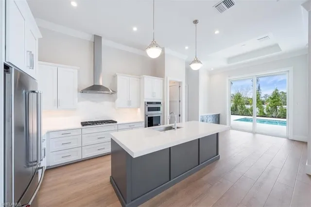 a large kitchen with kitchen island a stove a sink a center island and wooden floor