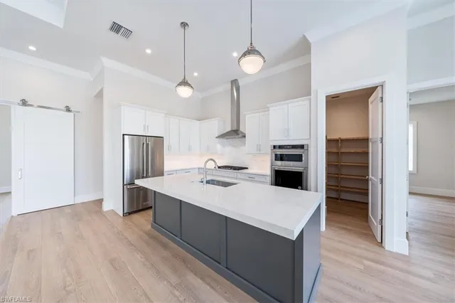 a kitchen with kitchen island a sink stainless steel appliances and wooden floor