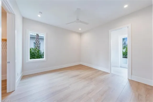 an empty room with wooden floor a ceiling fan and windows