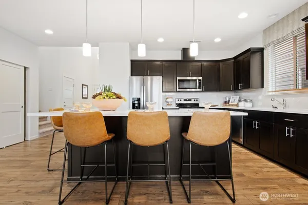 a kitchen with stainless steel appliances kitchen island granite countertop a dining table chairs microwave and sink