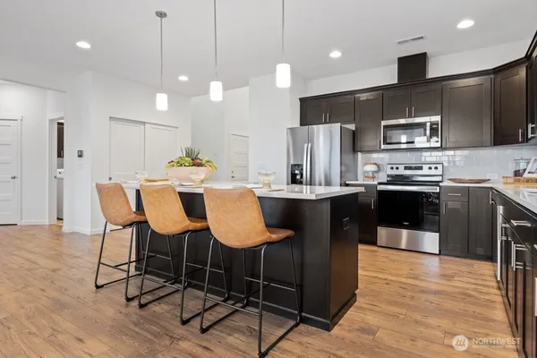 a kitchen with stainless steel appliances kitchen island granite countertop a table chairs and a refrigerator