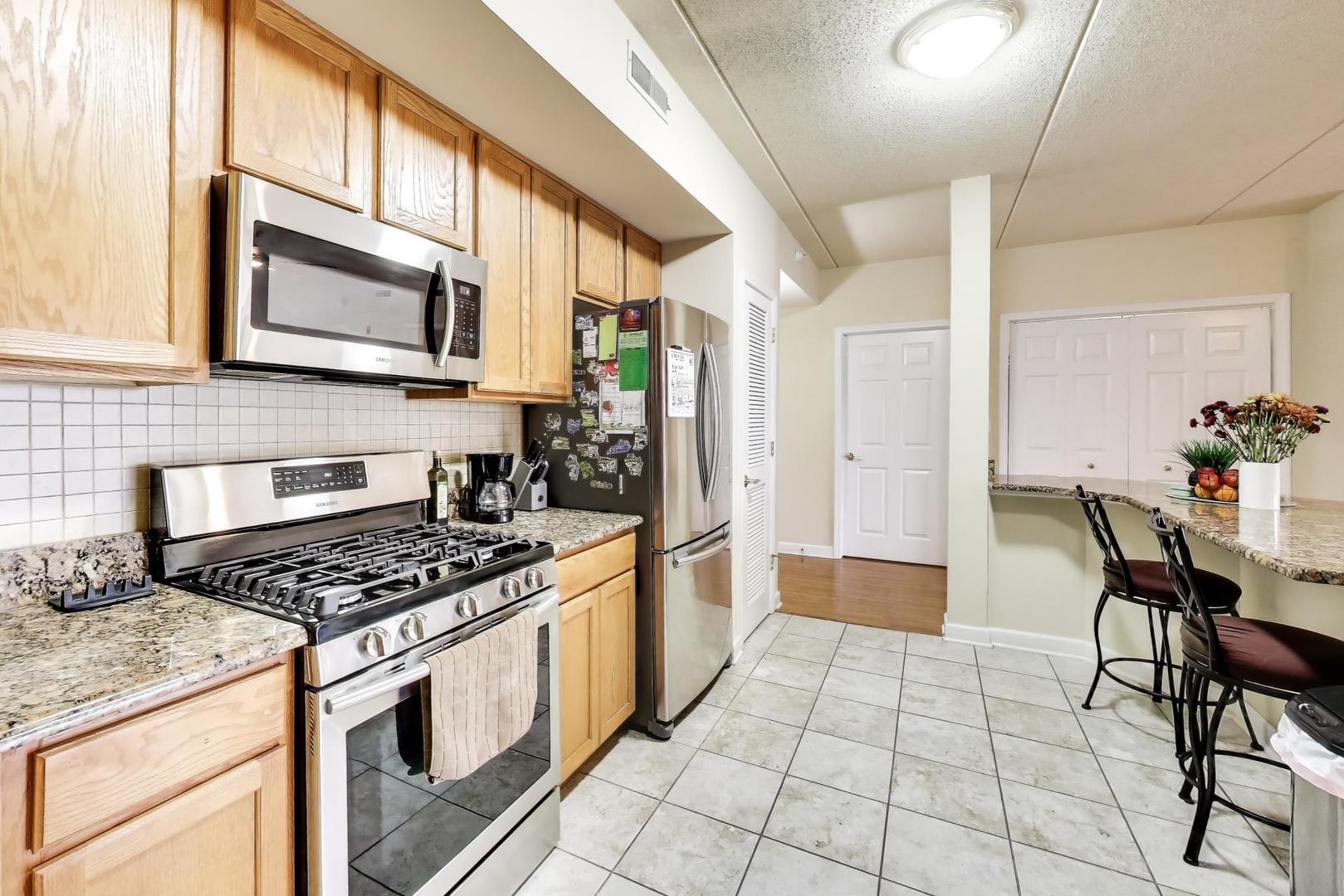 77 North Wolf Road, Unit 312 Melrose Park, IL 60164 - Photo 6 of 20 a kitchen with stainless steel appliances granite countertop a stove a sink and a refrigerator