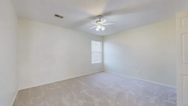 an empty room with a window and ceiling fan