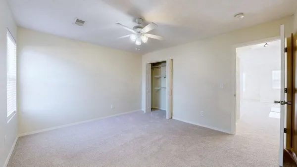 a view of an empty room with a chandelier fan