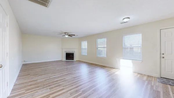 an empty room with wooden floor and windows