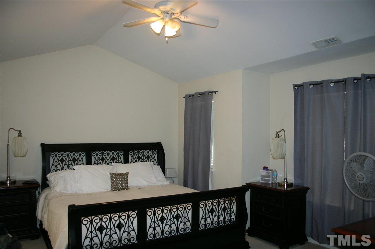 8207 Beaded Stone Street Raleigh, NC 27613 - Photo 15 of 23 a bedroom with a bed and a chandelier