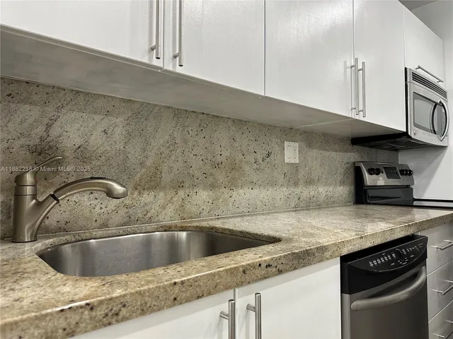 a close view of a sink and dishwasher in kitchen with granite countertop