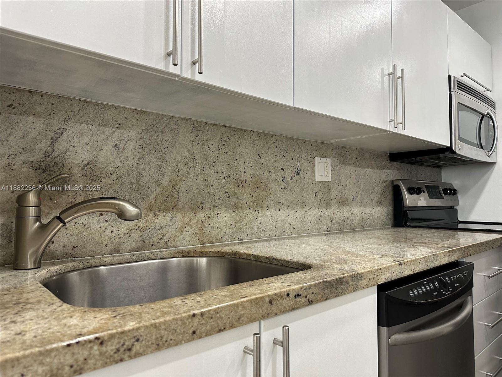 a close view of a sink and dishwasher in kitchen with granite countertop