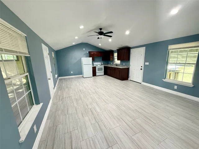 an empty room with wooden floor fireplace and windows