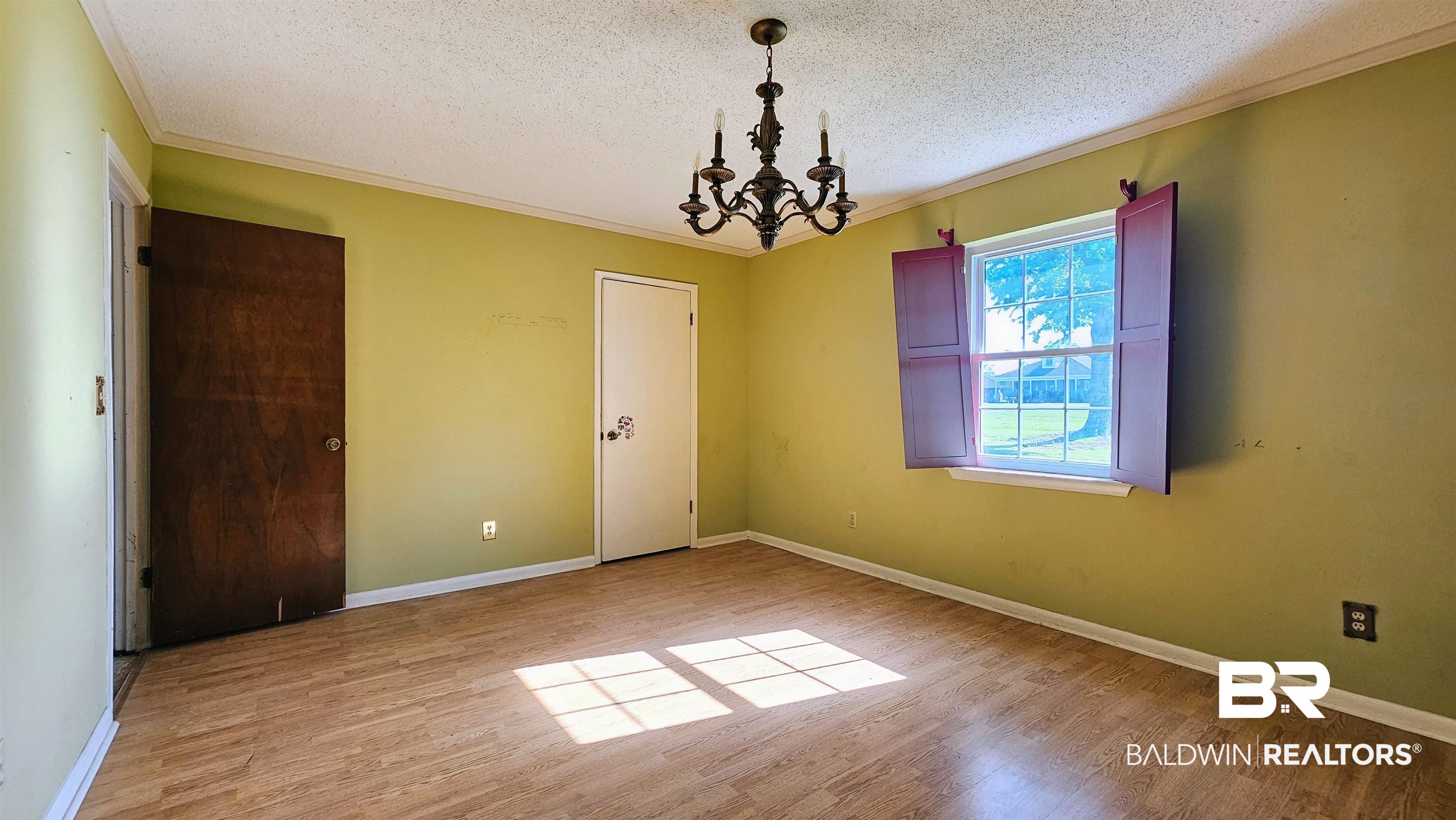 18824 Highway 41 Brewton, AL 36426 - Photo 28 of 40 Room featuring wood-finish flooring, a double-hung window with shutters, and a dark metal chandelier