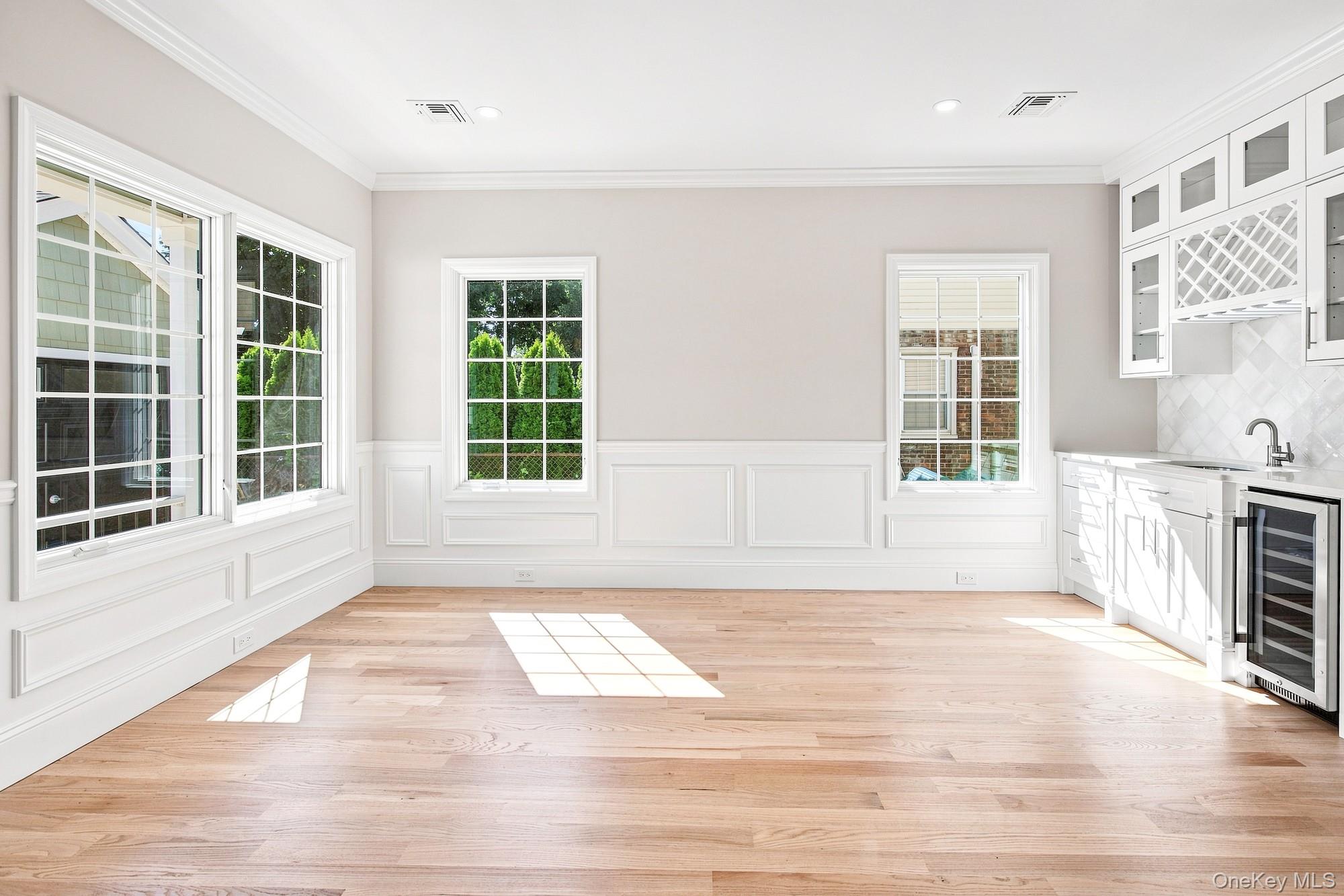 148 Latham Road Mineola, NY 11501 - Photo 12 of 27 Dining Room - light wood-finish flooring, multiple paneled windows, recessed lighting, built-in cabinetry with glass inserts, and a beverage cooler.