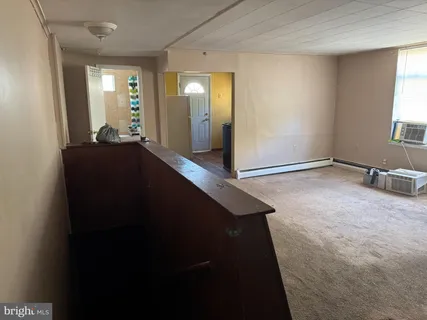 a view of a hallway to a room with wooden floor and windows