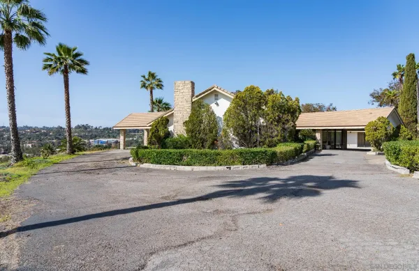 a front view of a house with a yard and palm trees