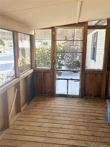 a view of a kitchen from an empty room with wooden floor and a window