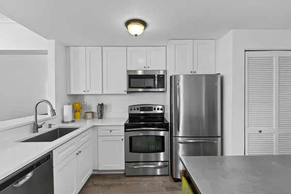 a kitchen with a refrigerator sink and white cabinets